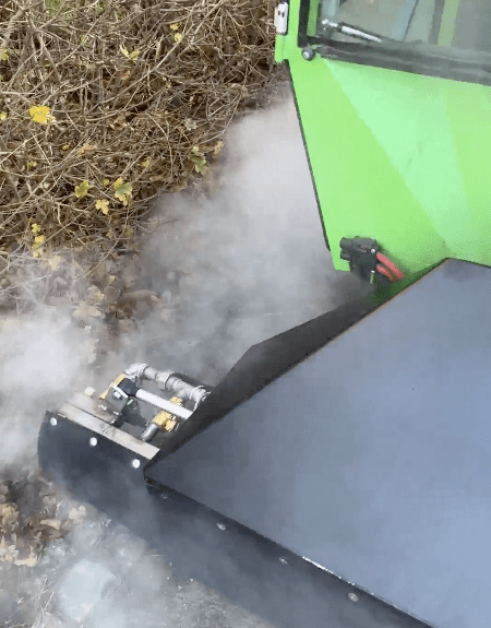 En Aqua-Cleaner maskine med dysebom sprøjter varm damp for miljøvenlig ukrudtsbekæmpelse på tørre buske og jord.